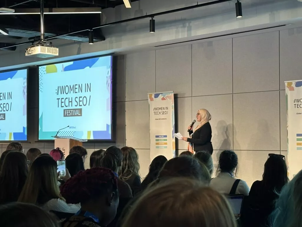 Women in Tech SEO: London Industry Event Recap 3 Photo of the opening remarks at the Women in Tech SEO (WTS) event in London 2024 – Founder Areej AbuAli speaking on stage.
